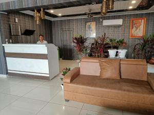 a man standing at a counter in a lobby with a couch at Nearmi Hotels Banquets Medanta IKEA Sector 47 - Gurugram in Gurgaon