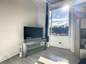 a living room with a tv and a large window at Appart chartreux baignoire massante ,à 2 minutes du centre! in Voiron