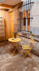 una mesa amarilla y dos sillas junto a un edificio en Studio rénové avec patio, coeur du centre ville en Besanzón