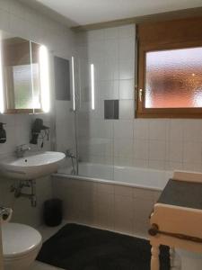 La salle de bains est pourvue d'un lavabo, d'une baignoire et de toilettes. dans l'établissement Magnifique appartement de montagne, à Loèche-les-Bains