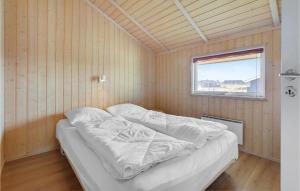 a bed in a wooden room with a window at 3 Bedroom Stunning Home In Thisted in Torsted