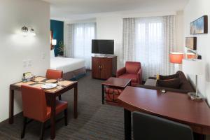 a hotel room with a bed and a desk and chairs at Residence Inn South Bend Mishawaka in South Bend