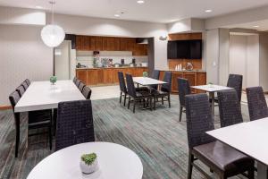 a dining room with tables and chairs and a kitchen at Residence Inn South Bend Mishawaka in South Bend