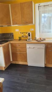 - une cuisine avec des placards en bois et un lave-vaisselle blanc dans l'établissement Les Hauts de Sochaux, à Sochaux