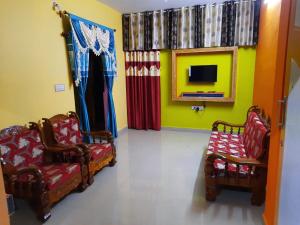a living room with two chairs and a tv at Green Land Estate Homestay 5 Rooms With Garden View in Madikeri