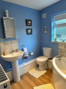 Baño azul con aseo y lavamanos en 1 Coach House - 3 bed period cottage built in 1686, en Tredegar