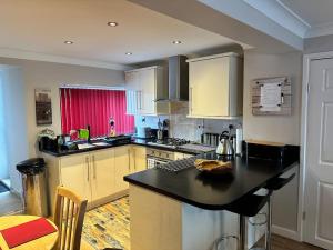 a kitchen with a black counter top and yellow cabinets at 1 Coach House - 3 bed period cottage built in 1686 in Tredegar
