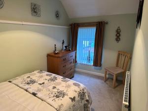 a bedroom with a bed and a dresser and a window at 1 Coach House - 3 bed period cottage built in 1686 in Tredegar