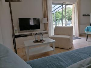 salon z telewizorem i krzesłem w obiekcie Maison chaleureuse proche plage du Gurp w mieście Grayan-et-lʼHôpital