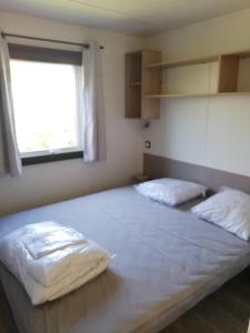 a bedroom with a large bed with two pillows on it at Mobilhome Clim Télé La Falaise 4 étoiles in Narbonne