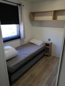 een kleine slaapkamer met een bed en een raam bij Mobilhome Clim Télé La Falaise 4 étoiles in Narbonne