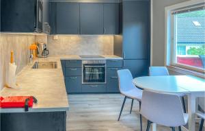 een keuken met blauwe kasten en een tafel met stoelen bij Beautiful Home In Hauge I Dalane With Wifi And 4 Bedrooms in Åmot