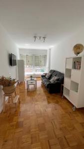ein Wohnzimmer mit einem schwarzen Sofa und Holzboden in der Unterkunft Apartamento Hórreo -San Pelayo- in Cangas de Onís
