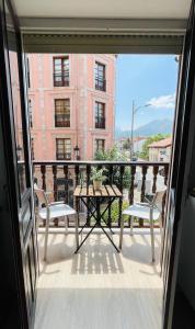 einen Balkon mit einem Tisch und Stühlen sowie ein Gebäude in der Unterkunft Apartamento Hórreo -San Pelayo- in Cangas de Onís
