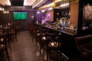 a man sitting at a bar in a restaurant at Villaggio Hotel Abu Dhabi in Abu Dhabi