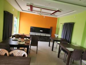 a living room with tables and a flat screen tv at Blooming Star Guest House in Mandarmoni