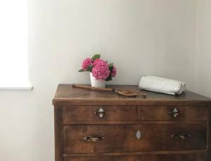 uma cómoda de madeira com um vaso de flores cor-de-rosa em Bella's Country House 