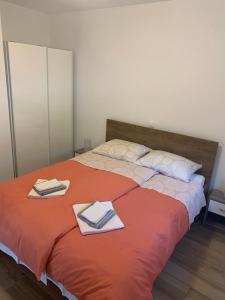 a bedroom with a large orange bed with towels on it at Apartman Nataša in Kostrena