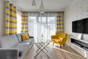 sala de estar con sofá gris y silla amarilla en Sopocka Bryza - Baltica Apartments, en Sopot
