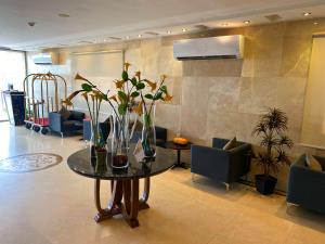 un vestíbulo con una mesa con flores y sillas en RAK Hotel Apartments en Yeda