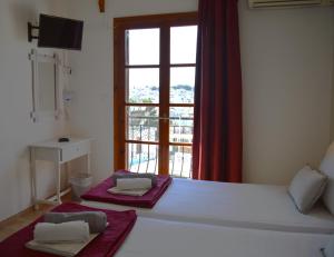 a bedroom with a bed with a window and two towels at Pension Mando in Skiathos