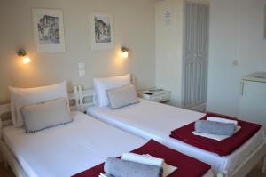 a white bedroom with two beds with towels on them at Pension Mando in Skiathos