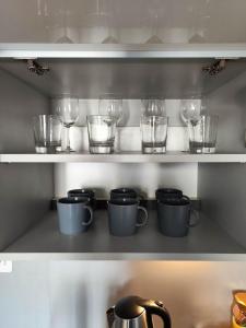 a shelf with glasses and pots and cups on it at Apartamenty Duo in Poznań