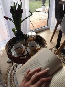 a woman reading a book with her hands on a table at Gorczańska Chatka in Osobie