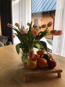 Gorczańska Chatka في Osobie: مزهرية مليئة بالورود والفواكه على طاولة