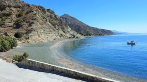 una barca in acqua vicino a una montagna di Villa Tzortzaki-Ifestos /Kalikovrextis Beach Crete a Térsa