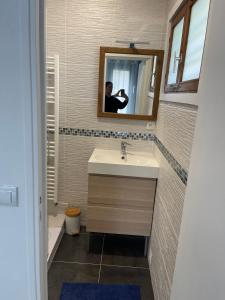 un homme prenant une photo d'une salle de bains avec lavabo dans l'établissement gite La briquette 6 personnes proche RER D, à Combs-la-Ville