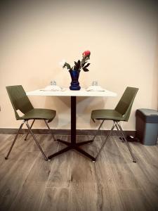 a table with two chairs and a vase with flowers on it at Les Résidences de Gorée Porto-Novo in Porto-Novo