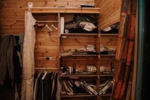 a closet with wooden walls and racks of clothes at סיגליות במדבר in Niẕẕane Sinay