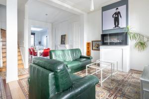 a living room with a green leather couch and a tv at Maison Famille-Confort-Terrasse Jardin-Vue Cathédrale in Amiens
