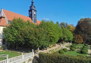 a church with a clock tower and a garden at Große FeWo im Schlossensemble Seußlitz in Bornitz