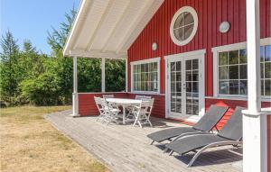 een rood huis met een tafel en stoelen op een patio bij Gorgeous Home In Aakirkeby With Wifi in Vester Sømarken