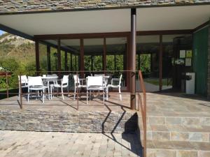 a patio with white chairs and tables on a building at Hotel Rural Rio Molinar in Ranera