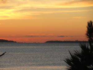 einen Sonnenuntergang über einem Wasserkörper in der Unterkunft Cannes Terrace Beach Front & Sea view in Cannes