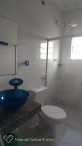 y baño con aseo y lavamanos azul. en Pousada Lirio dos Vales, en Prado