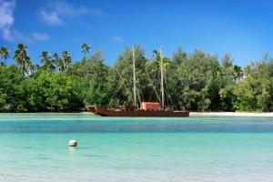 a boat sitting in the water next to a beach at Avana Waterfront Apartments in Rarotonga