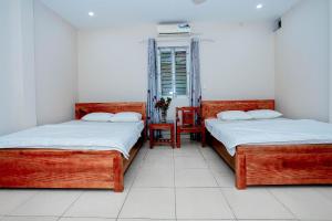 two twin beds in a room with a window at Nhà nghỉ Hoa Lạc Tiên in Bản Giỏ (1) +29 photos