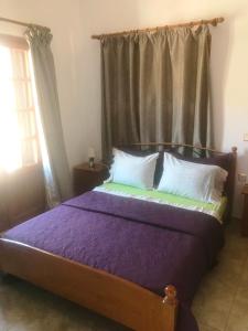 um quarto com uma cama com lençóis roxos e uma janela em Villa Maria em Kalymnos
