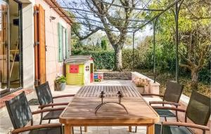einen Holztisch und Stühle auf einer Terrasse mit einem Hundehaus in der Unterkunft Stunning Home In Salon-de-provence With Outdoor Swimming Pool, Wifi And 3 Bedrooms in Salon-de-Provence