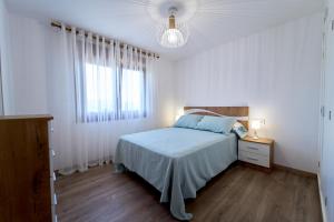 a white bedroom with a bed and a window at O Lar de Lola in Mondariz