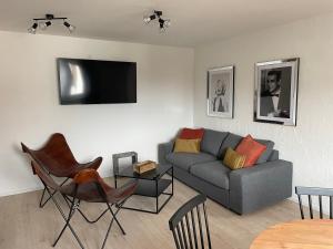 uma sala de estar com um sofá e uma televisão na parede em Freigeist Apartments em Haßloch