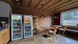 Alpinum Hostel في ببيرفيير: غرفة طعام مع ثلاجة وطاولة