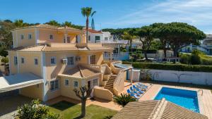 une grande maison jaune avec une piscine dans l'établissement Amora Classic Villa, à Vilamoura