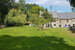 un arbre dans la cour d'une grande maison dans l'établissement Charmant gîte avec poêle à bois, à Pleslin-Trigavou