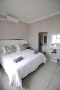 - une chambre blanche avec un grand lit blanc et des oreillers dans l'établissement Stone Ridge Luxury Self Catering Unit, à St Lucia
