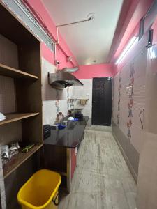 a kitchen with pink walls and a yellow stool at ROOP AMRIT GUEST HOUSE in Agartala